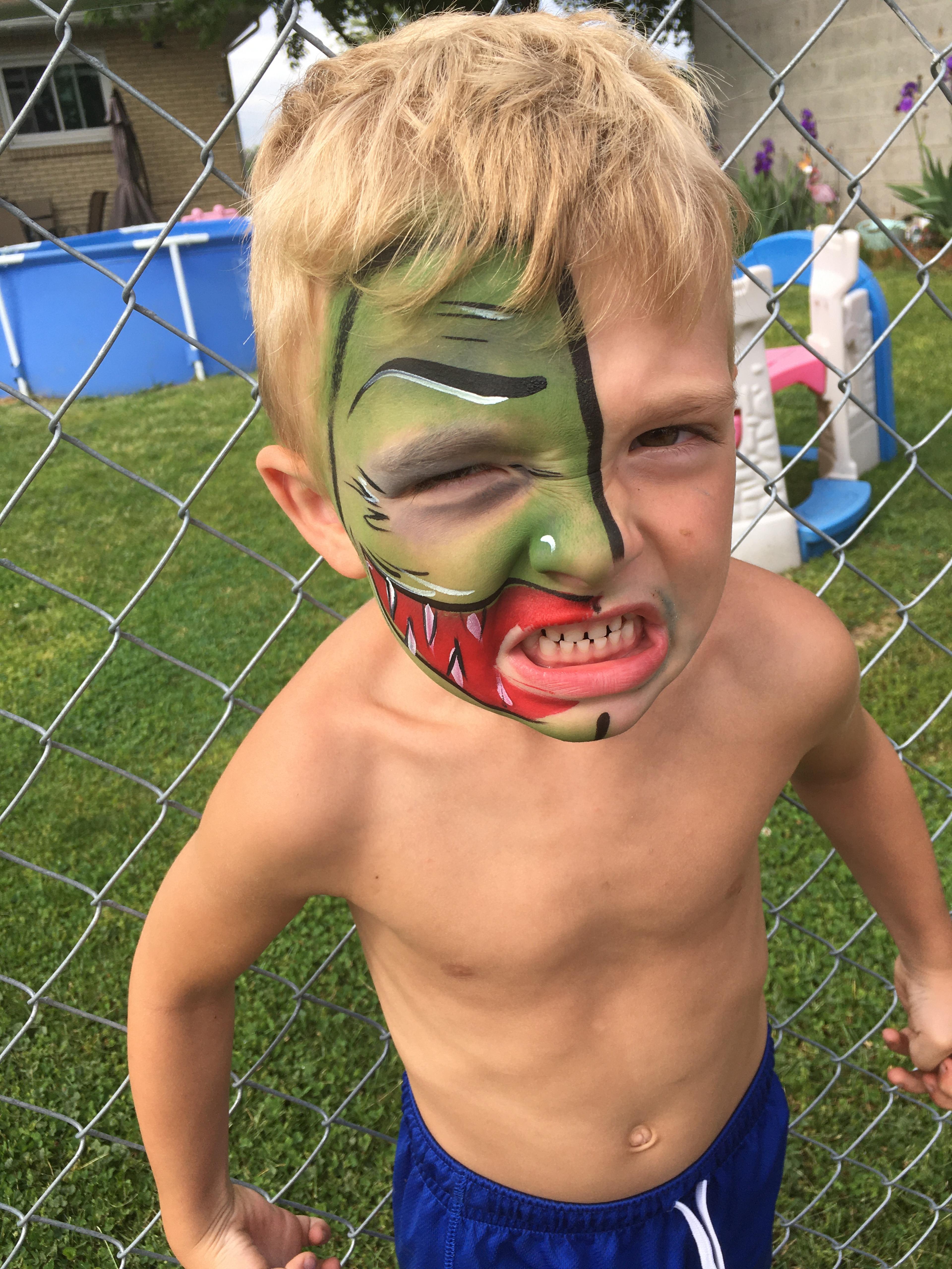Young kid with half his face painted like a monster